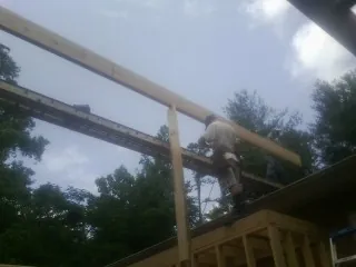Carpenter setting a ridge beam over a new addition frame — Ice Dam Removal by Roofing Brothers in Holiday