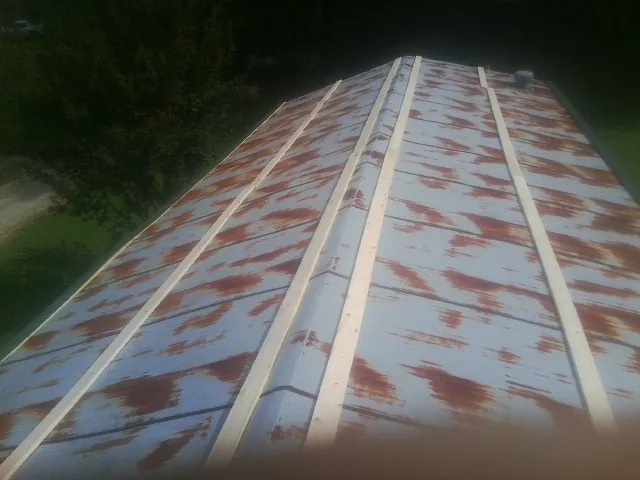 Rusted metal roof panels with new wood purlins before replacement — Storm Damage Roof Repair in Holiday by Roofing Brothers