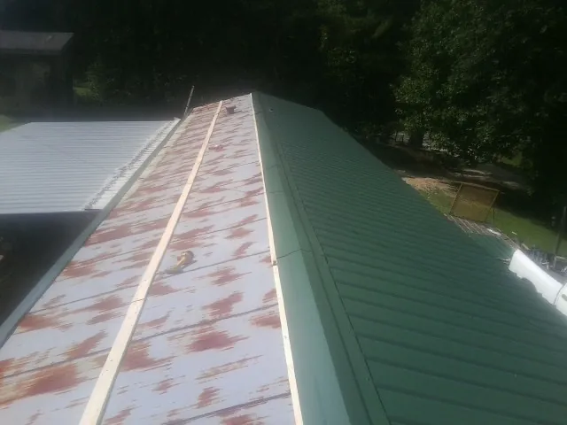 Old rusted panels beside newly installed green metal roofing — Wind Damage Roof Repair by Roofing Brothers in Holiday