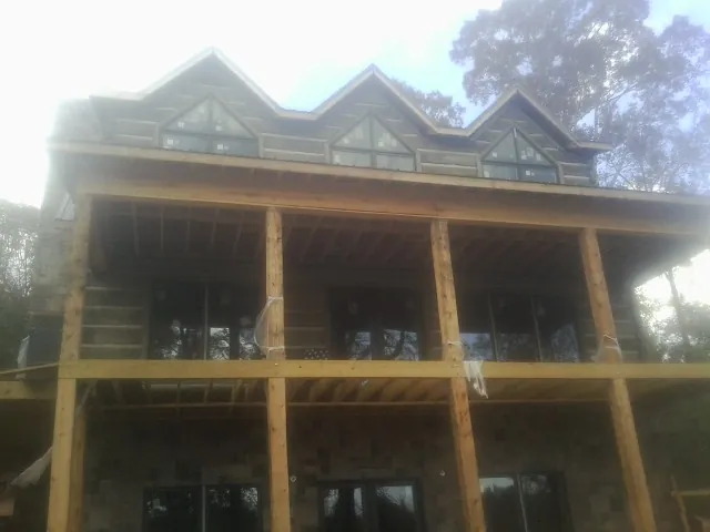 Dormers and porch framing on a large log home under construction — Roof Coating work by our crew in Holiday