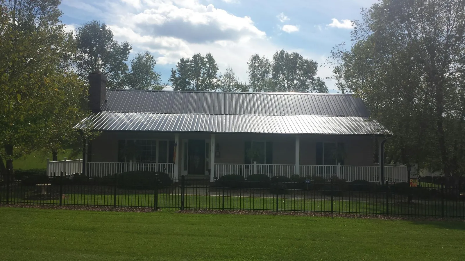 Gray metal roof on a brick ranch with a full width front porch — Gutter Guard Installation work by our crew in Holiday