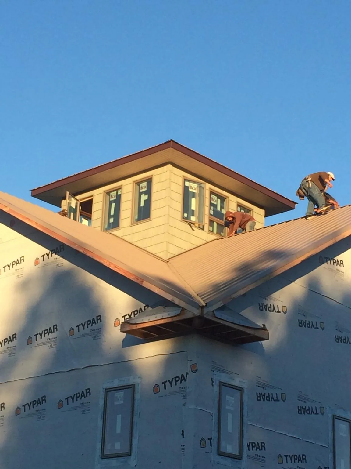 Roofers working around a rooftop cupola on a new metal roof at sunset — Roof Waterproofing in Holiday by Roofing Brothers